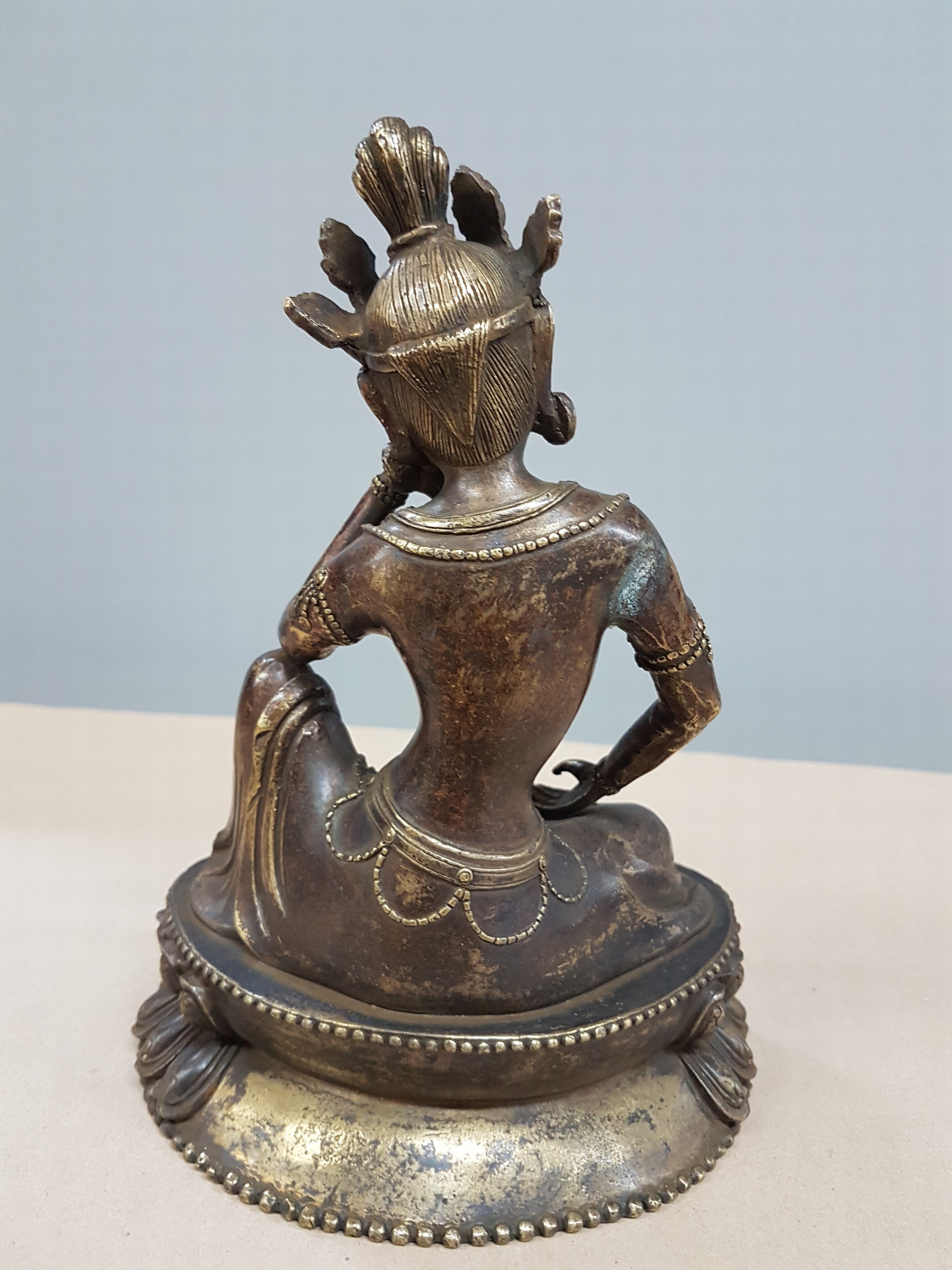 Detail c: Buddha, Tibet, 20. Jh., Bronze, patiniert, auf Lotussockel, eine Hand aufgestützt, H. ca. 21 cm