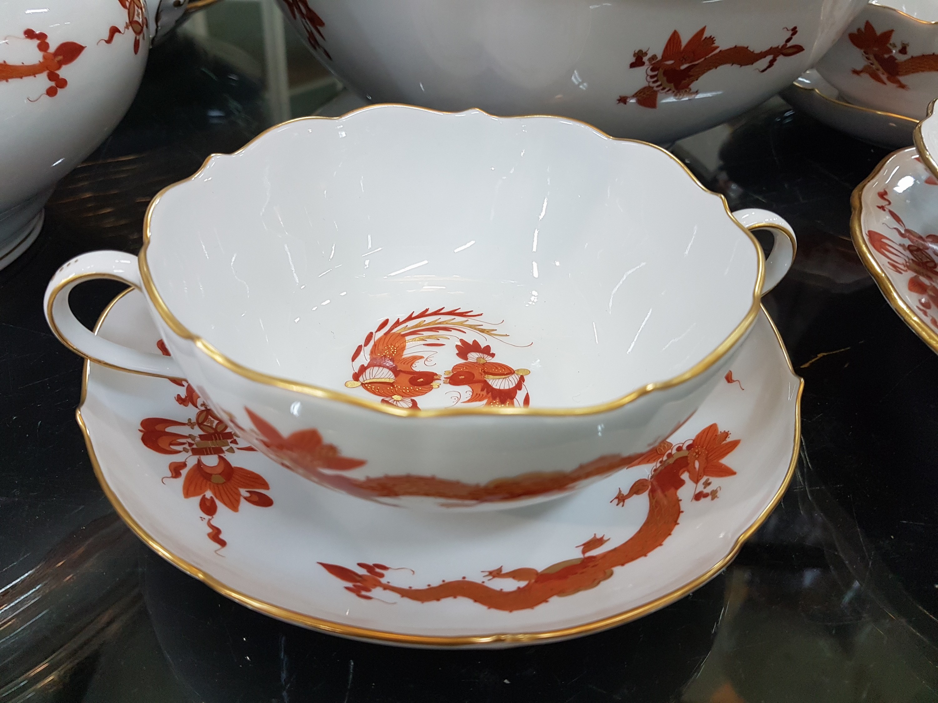 Detail e: Umfangreiches Tafelservice, Meissen, 20. Jh., roter Hofdrache, golden gehöht, 11 Menueteller, 8 Teller D. 20 cm, 6 Suppentassen mit Untertassen, 2 ...