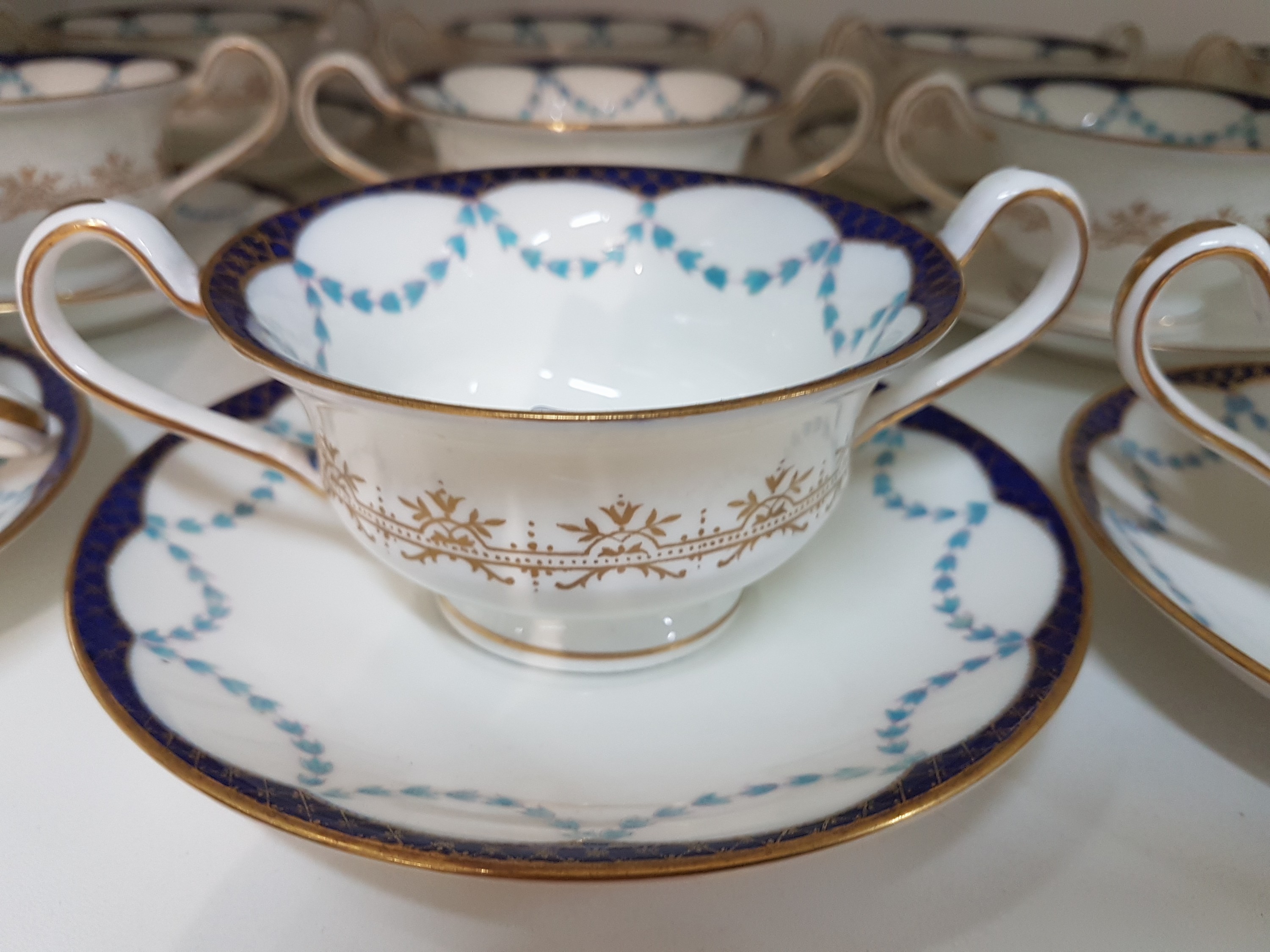 Detail c: 12 Gedecke Ribbon and Roses, Wedgwood, London, um 1900, Porzellan, farbiger Dekor mit Goldstaffage, 12 Doppelhenkeltassen mit UT, Alterssp.