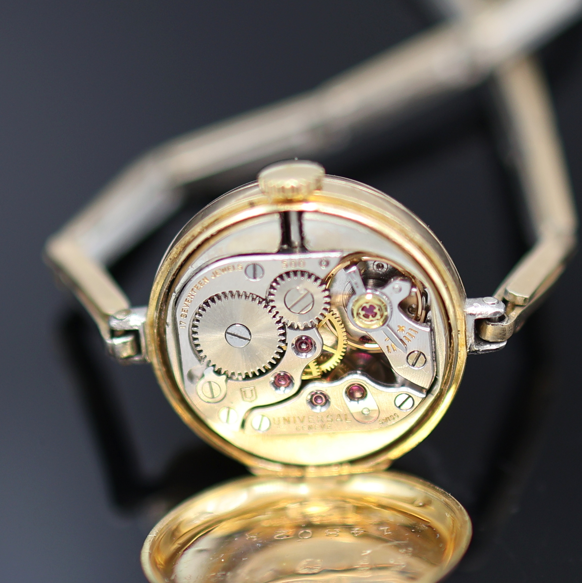 Detail e: Frühe mit Diamanten besetzte Armbanduhr in GG 750/000, Schweiz um 1920, Handaufzug, z. T. rhod. gefedertes Goldband, Scharnierboden, Lünette m. ...