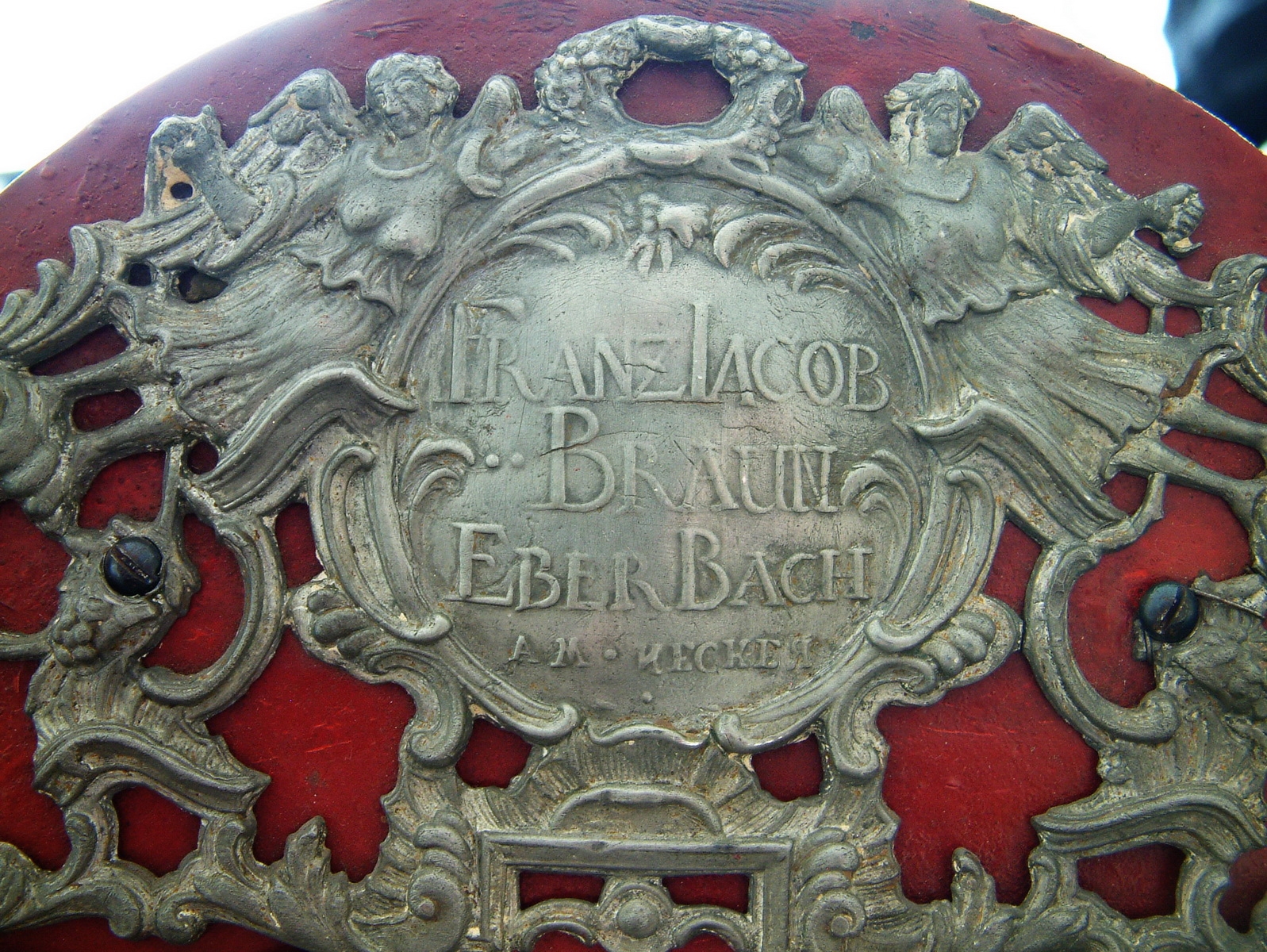 Detail a: Werk einer Wanduhr/Standuhr, Franz Jacob Braun Eberbach am Neckar, im 1780, Bogenzifferblatt, Eisen rot gefaßt, Eckverzierungen, im Arkus ...