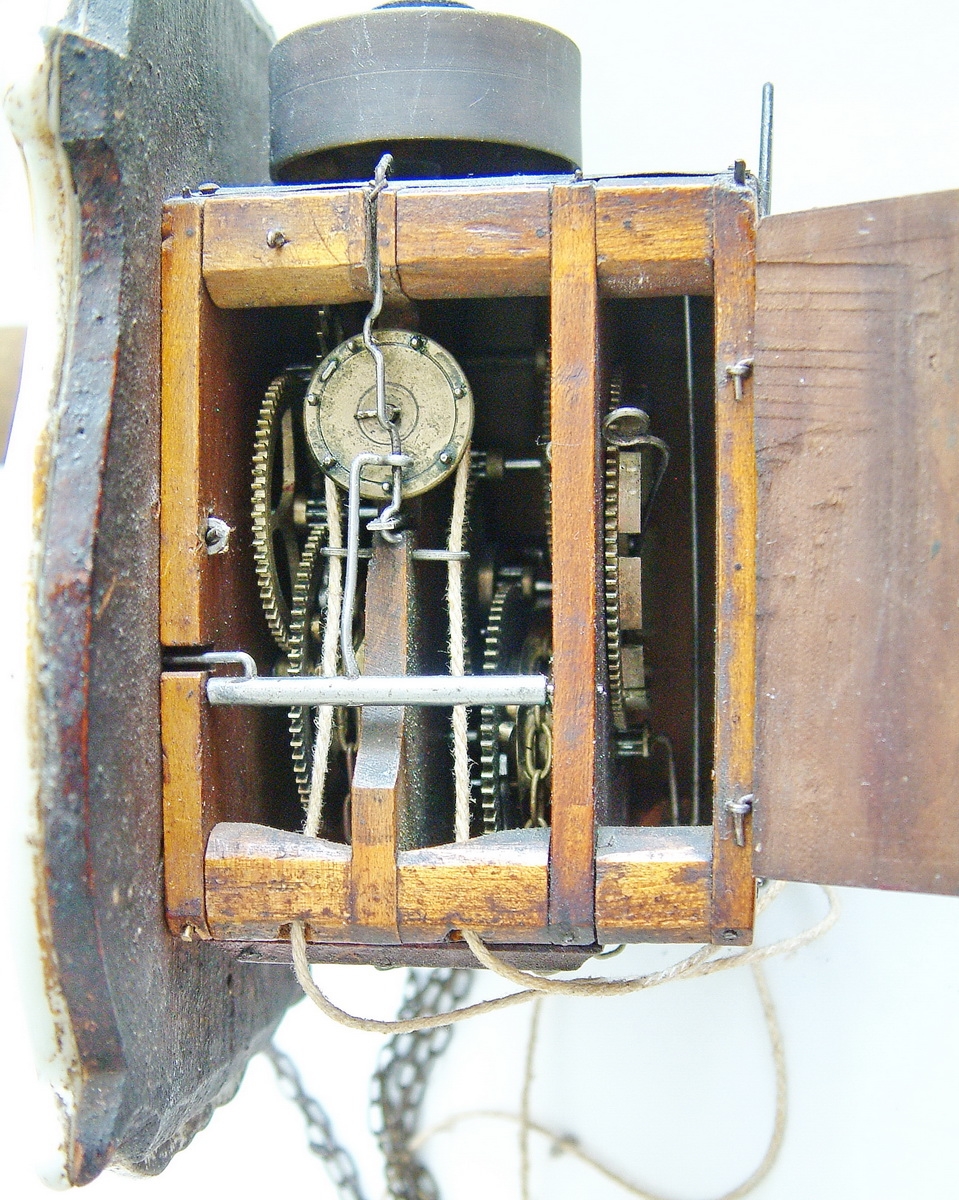 Detail a: Jockele-Uhr, Schwarzwald um 1850/60, Porzellanschild in sog. Tropfenform, mit Flußlandschaft bemalt, Goldbemalung berieben, Holz unterfüttert, ...