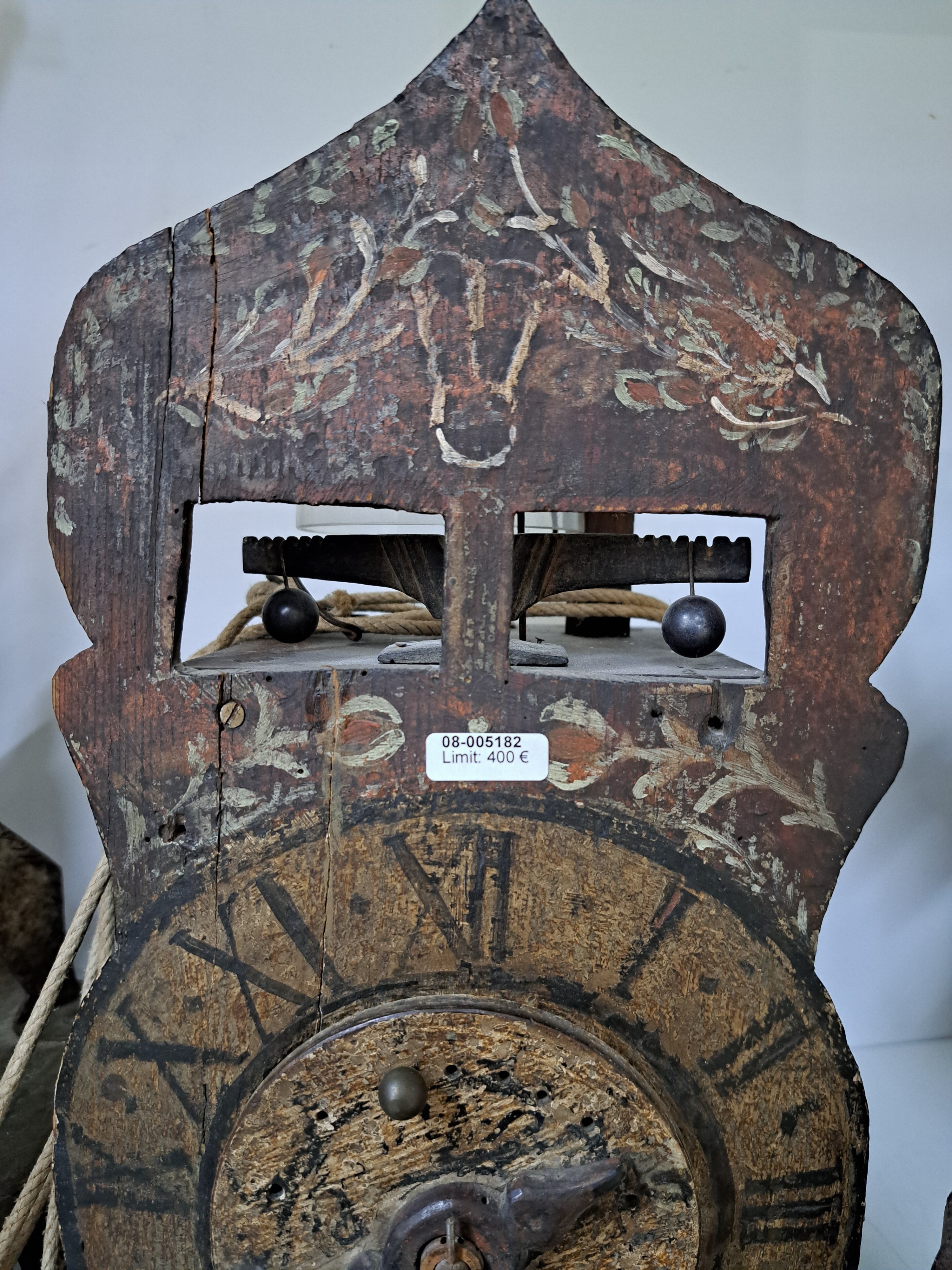 Detail d: Frühe Holzräderuhr, Schwarzwald um 1750, bemaltes Schild (altersbedingt erhalten), mit sichtbarem Waagbalken mit Ausgleichsgewicht, Holzräder und ...