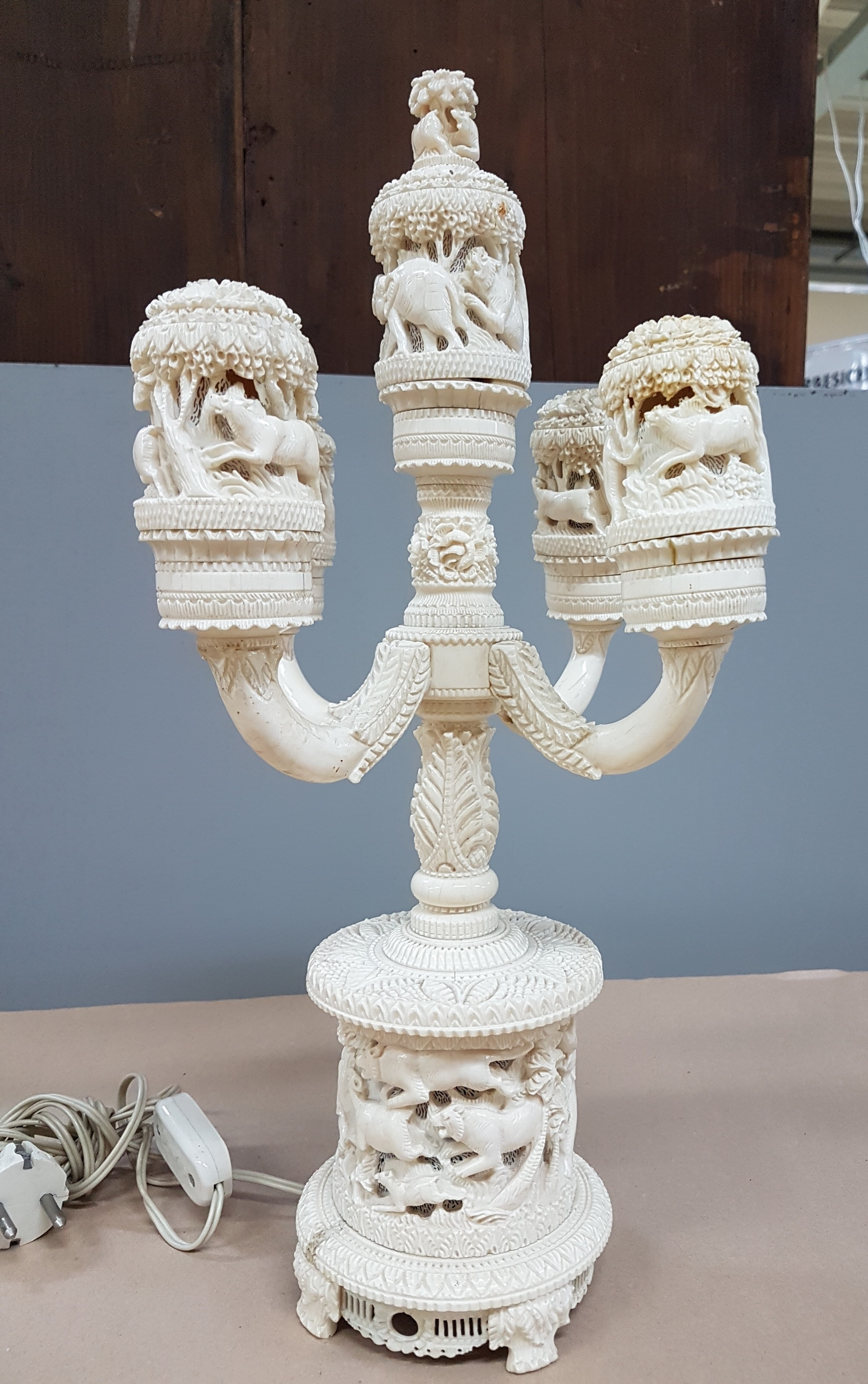 Detail d: Fünfarmige Elfenbeinleuchte, Indien, um 1930, Sockel aus einem Hohlstück eines Stoßzahnes, reich geschnitzt, mit exotischen Wildtieren, u.a. ...