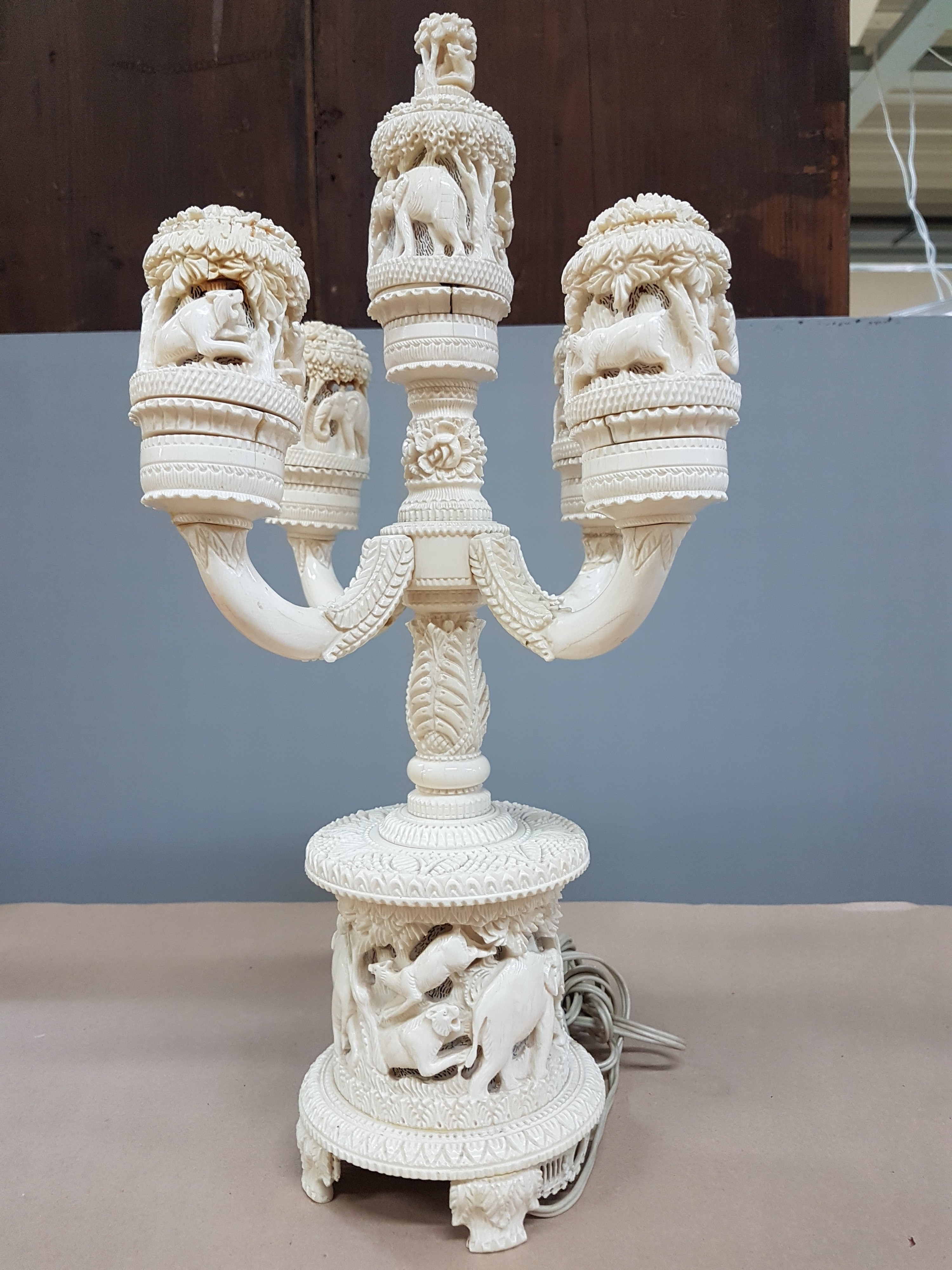 Detail n: Fünfarmige Elfenbeinleuchte, Indien, um 1930, Sockel aus einem Hohlstück eines Stoßzahnes, reich geschnitzt, mit exotischen Wildtieren, u.a. ...