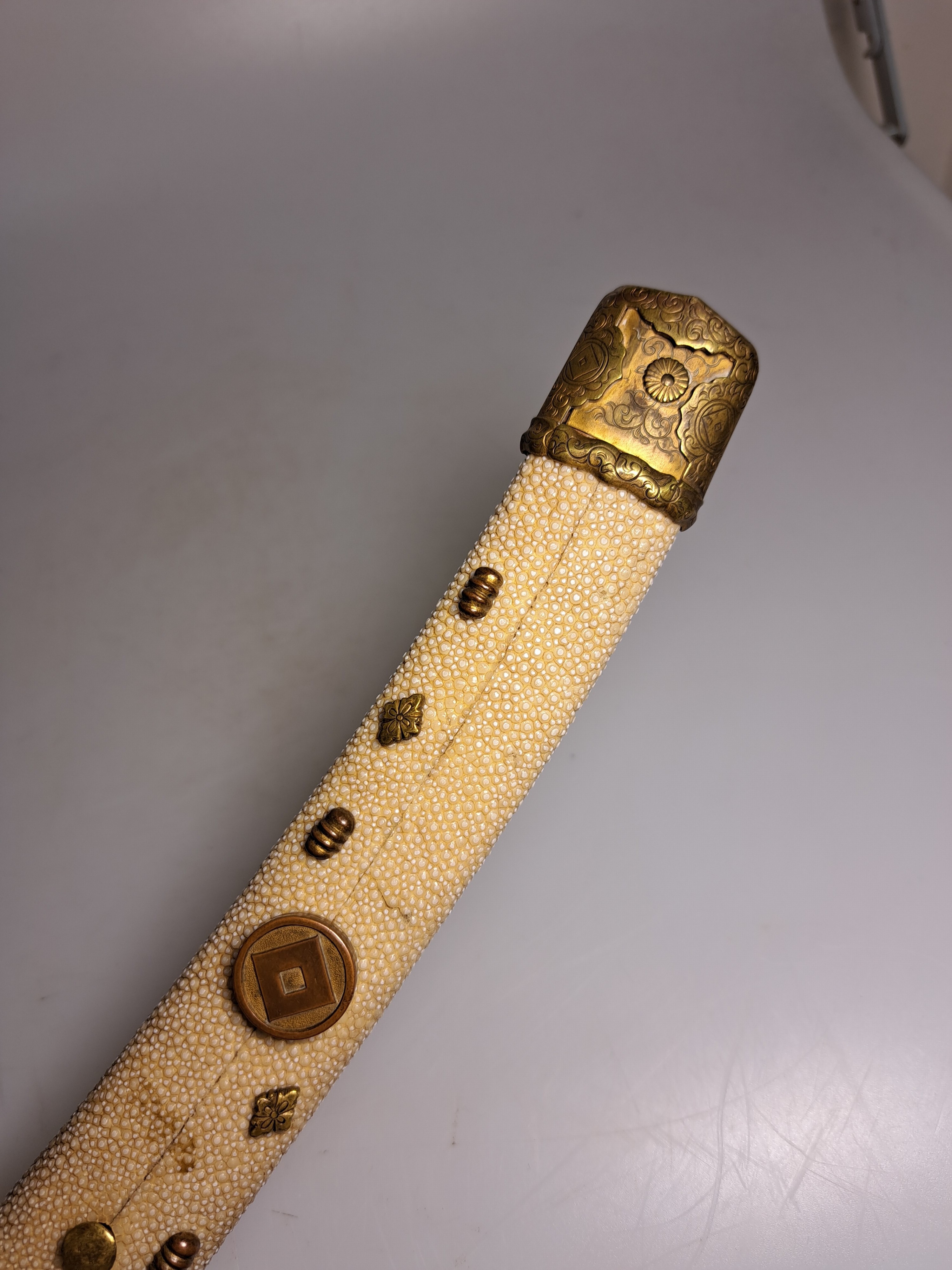 Detail b: Katana, Japan, 1. Hälfte 20. Jh., Griff mit Rochenhaut und 12 kleinen Menukis, Messingmontierung fein graviert, Scheide jaspisfarben mit Sterndekor, ...