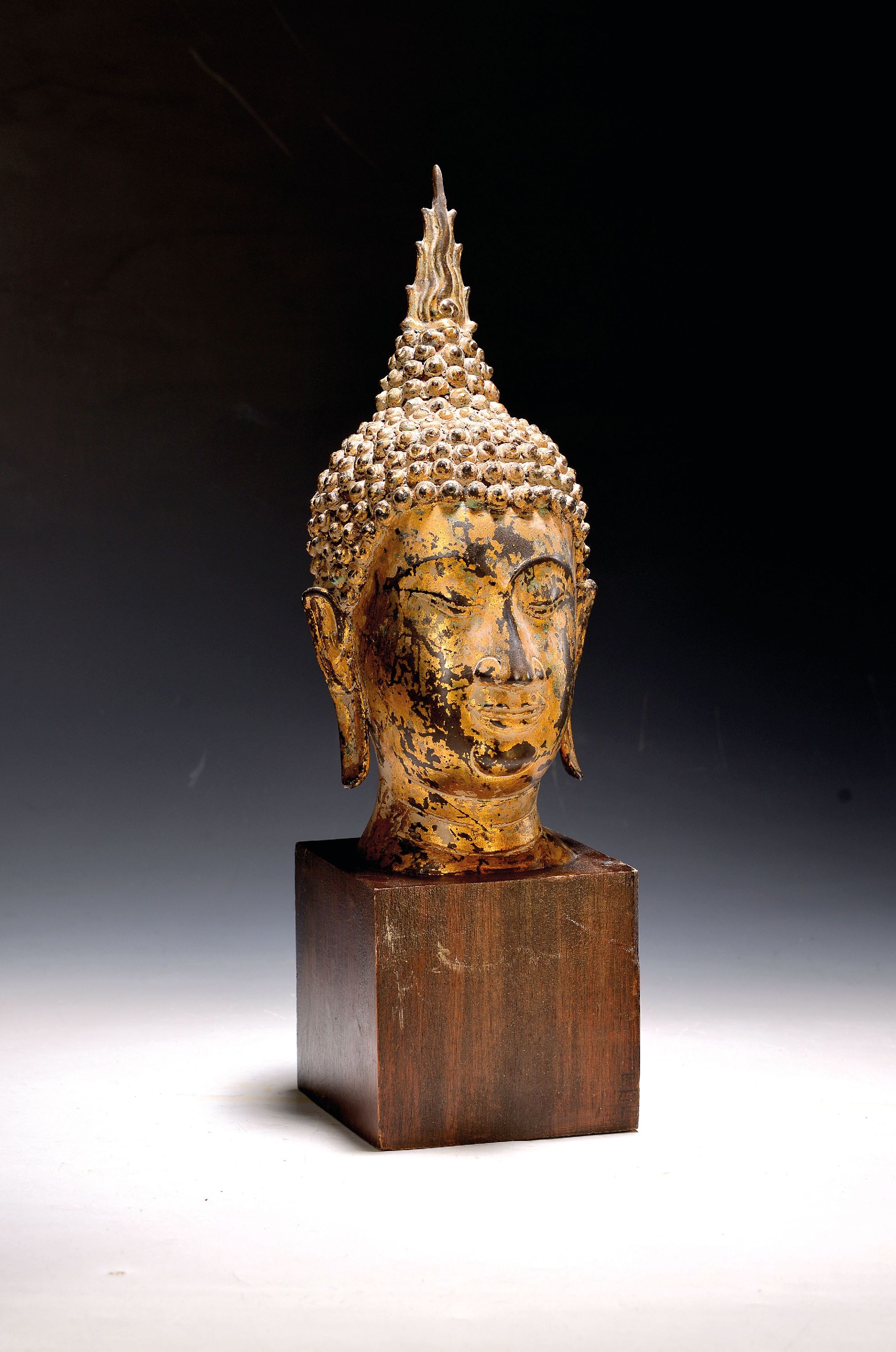 Image 27136648 - Buddhakopf, thailändisch, 20.Jh., Metall, blattvergoldet, auf Holzsockel, H. 44 cm
