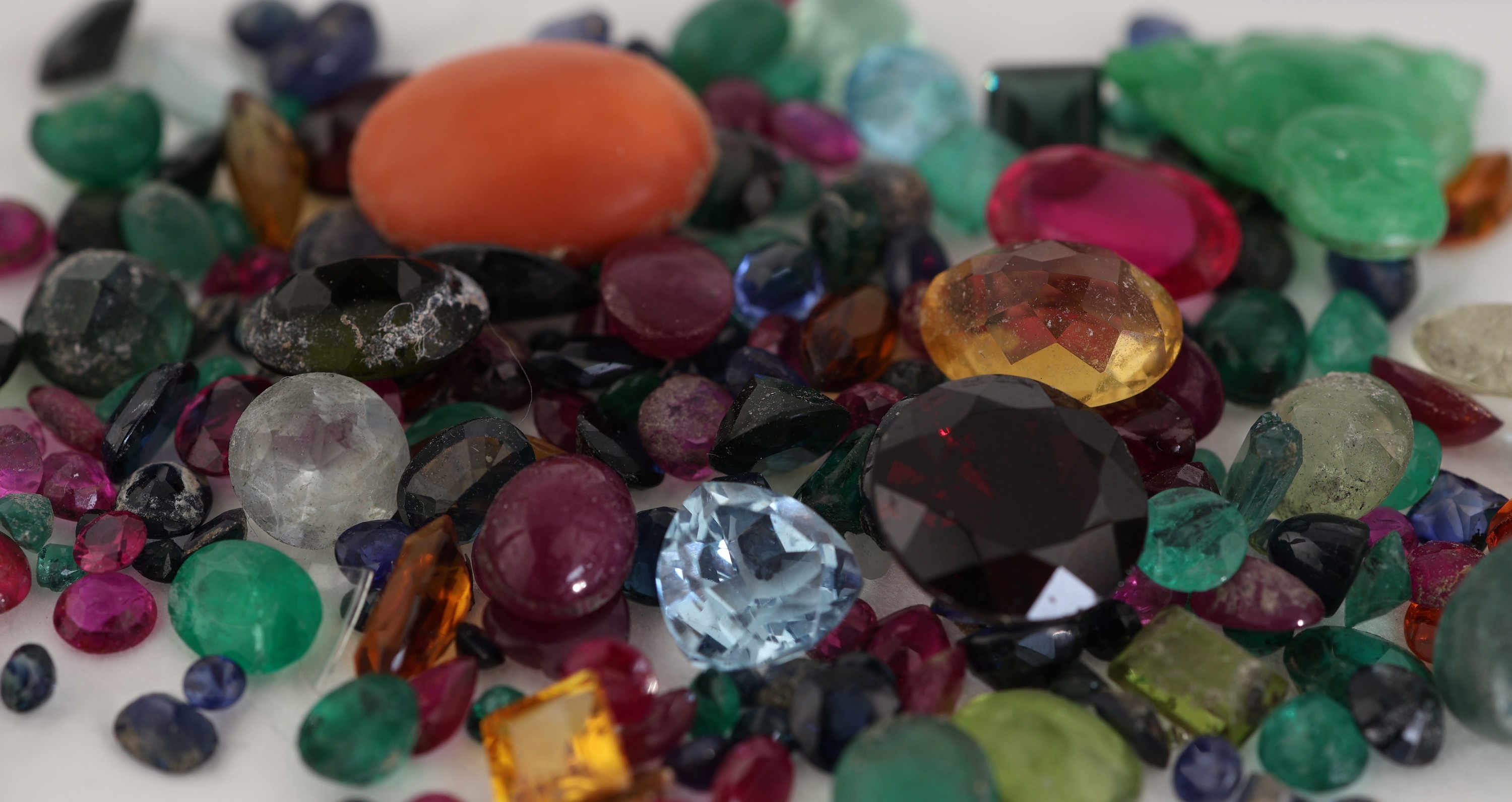 Detail a: Lot div. Farbsteine, zus. ca. 124.91 ct, u.a. Rubine, Saphire, Smaragde, Blautopase (beh.), Citrine, Korallencabochon, teilw. besch., Ausfassware, ...